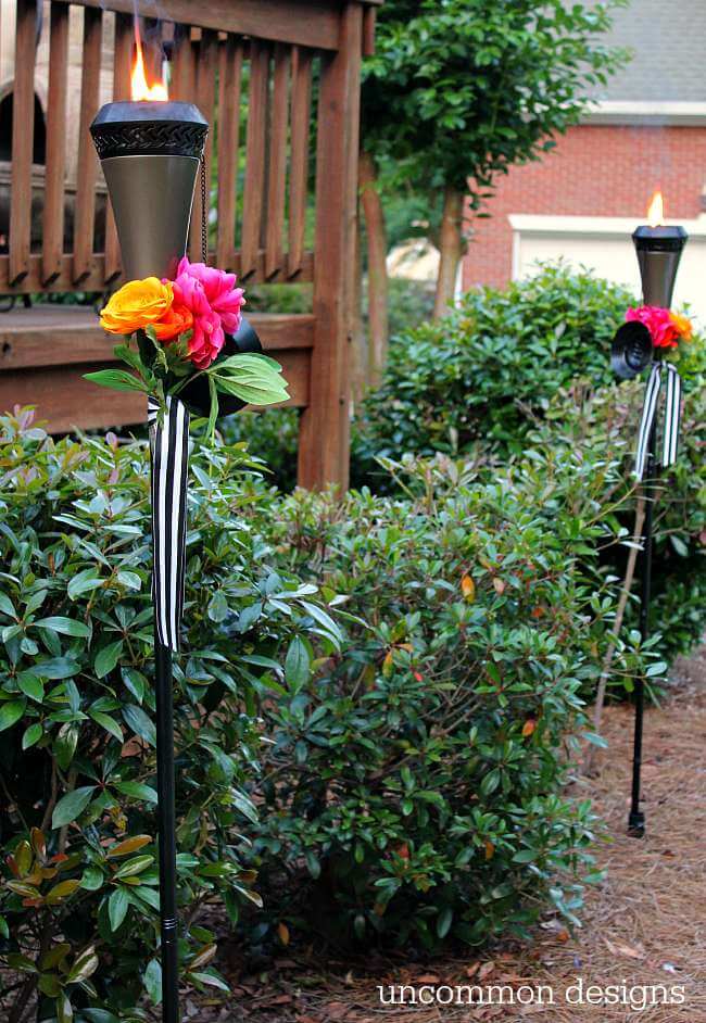 Dress up your tiki torches.  These floral tiki torches would be gorgeous for a wedding or garden party.  Add a few faux flowers and some striped ribbon and you are done! by Uncommon Designs 