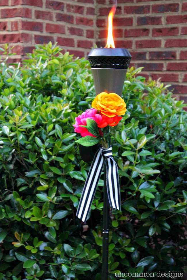 Dress up your tiki torches.  These floral tiki torches would be gorgeous for a wedding or garden party.  Add a few faux flowers and some striped ribbon and you are done! by Uncommon Designs 