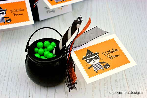 We decided to make witches brew treats out of miniature cauldrons and candies. We were able to pick up all of the supplies at our local craft store which was so convenient. We needed green Sixlet candies, miniature cauldrons, black and white striped candy sticks, and various ribbons. First, we tied the cards on to the handle of the cauldron with a fun assortment of Halloween ribbons, then we filled it up with the green candies for our brew and used the candy stick as our wooden stir stick. That is it… so cute and so easy! These make perfect classroom treats, too!