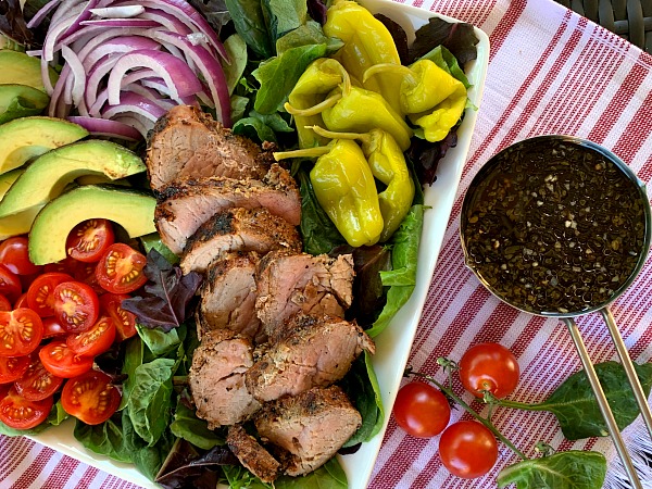 Fire up the grill for this delicious and light recipe for garlic and cracked black pepper grilled pork tenderloin salad with loads of toppings. A great grilling recipe for summer!