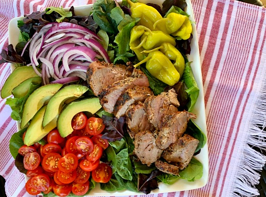 Fire up the grill for this delicious and light recipe for garlic and cracked black pepper grilled pork tenderloin salad with loads of toppings. A great grilling recipe for summer!