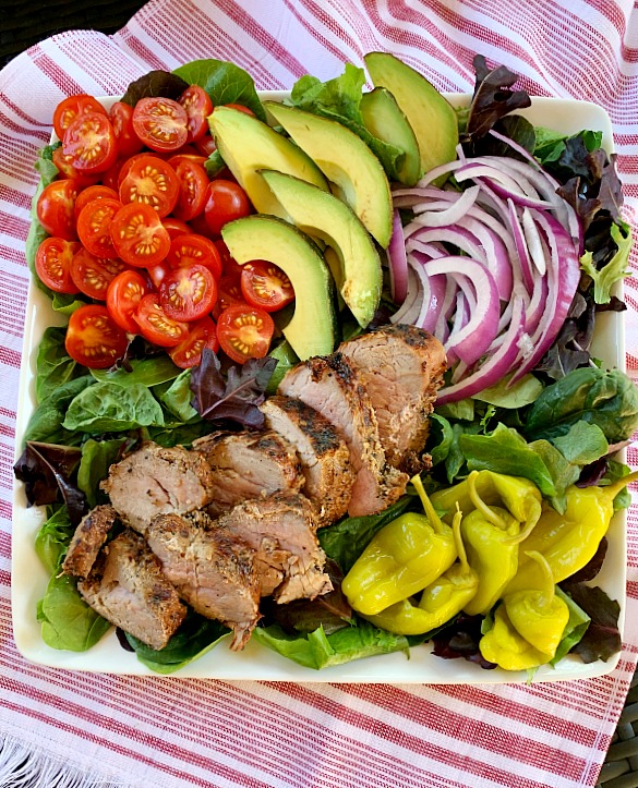 Fire up the grill for this delicious and light recipe for garlic and cracked black pepper grilled pork tenderloin salad with loads of toppings. A great grilling recipe for summer!